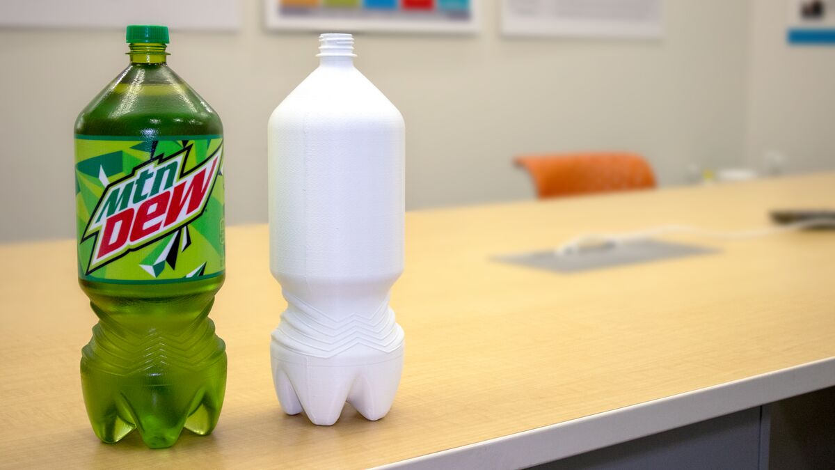 Mountain Dew 2-liter bottle next to its white 3D printed redesign prototype printed on a Stratasys J55