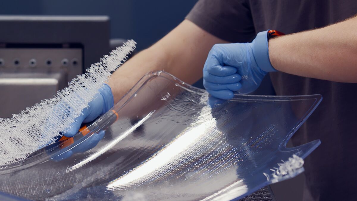 Technician removing a clear Somos WaterClear Ultra SLA part from a Stratasys Neo800 build platform