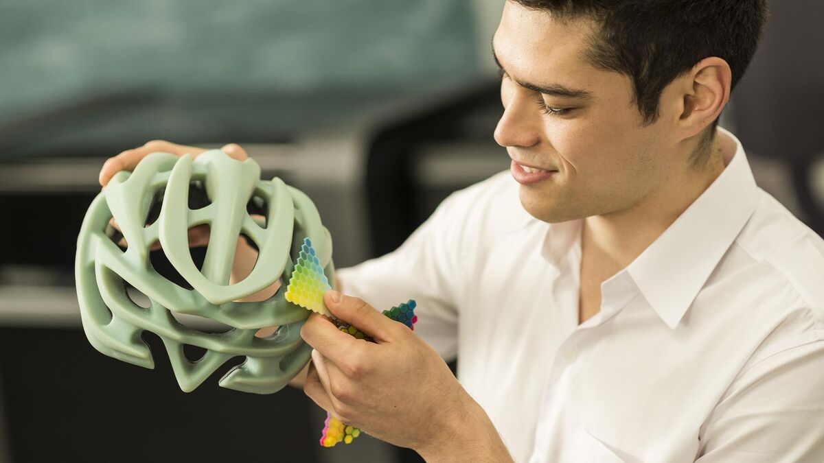 Product designer reviewing a multi-color 3D printed bicycle helmet prototype
