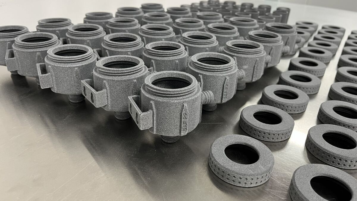 Rows of gray nylon parts 3D printed on a Stratasys H350 SAF printer after cleaning