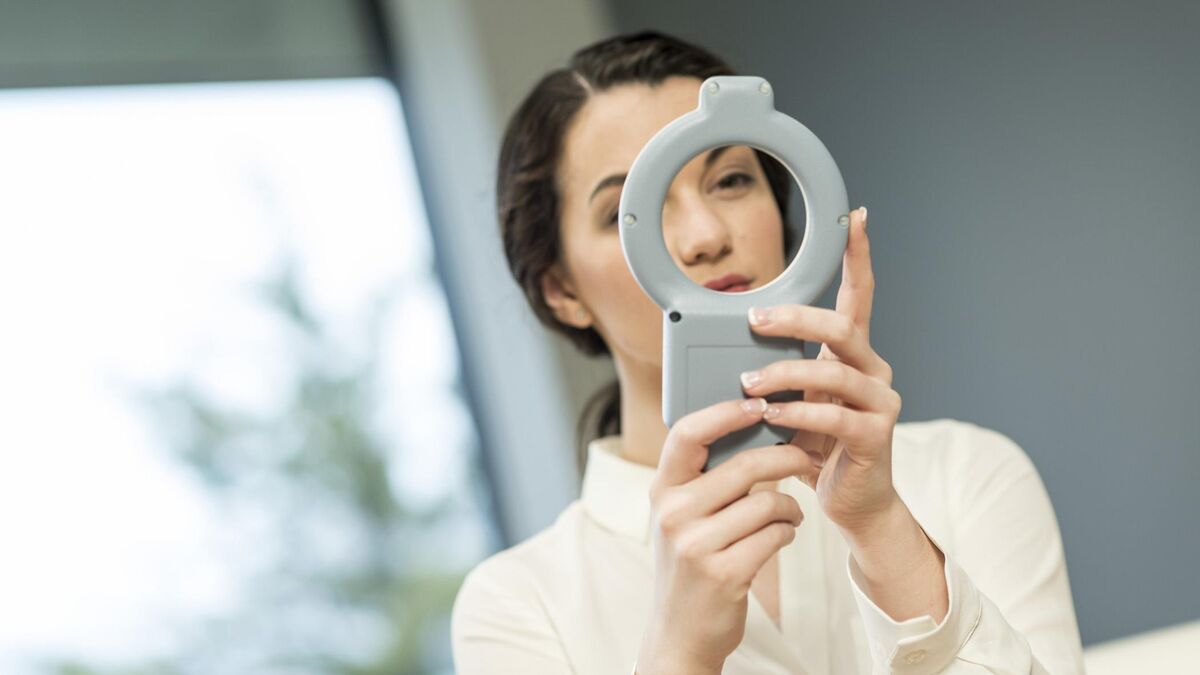 Woman holding a gray 3D printed medical device prototype up to the light