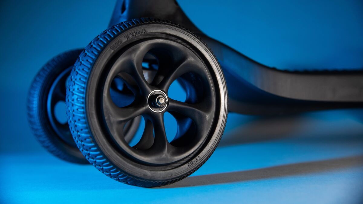 3D printed push scooter wheel and fork prototype on a blue background