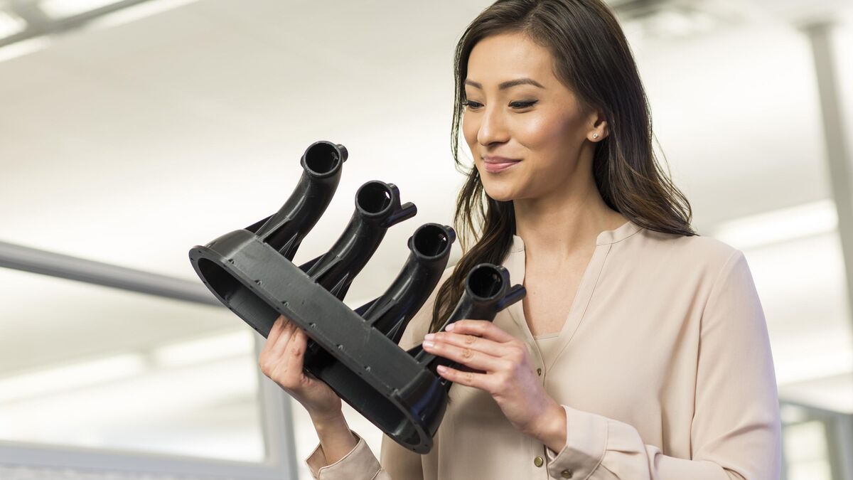 Woman holding a black 3D printed multi-branch air duct prototype