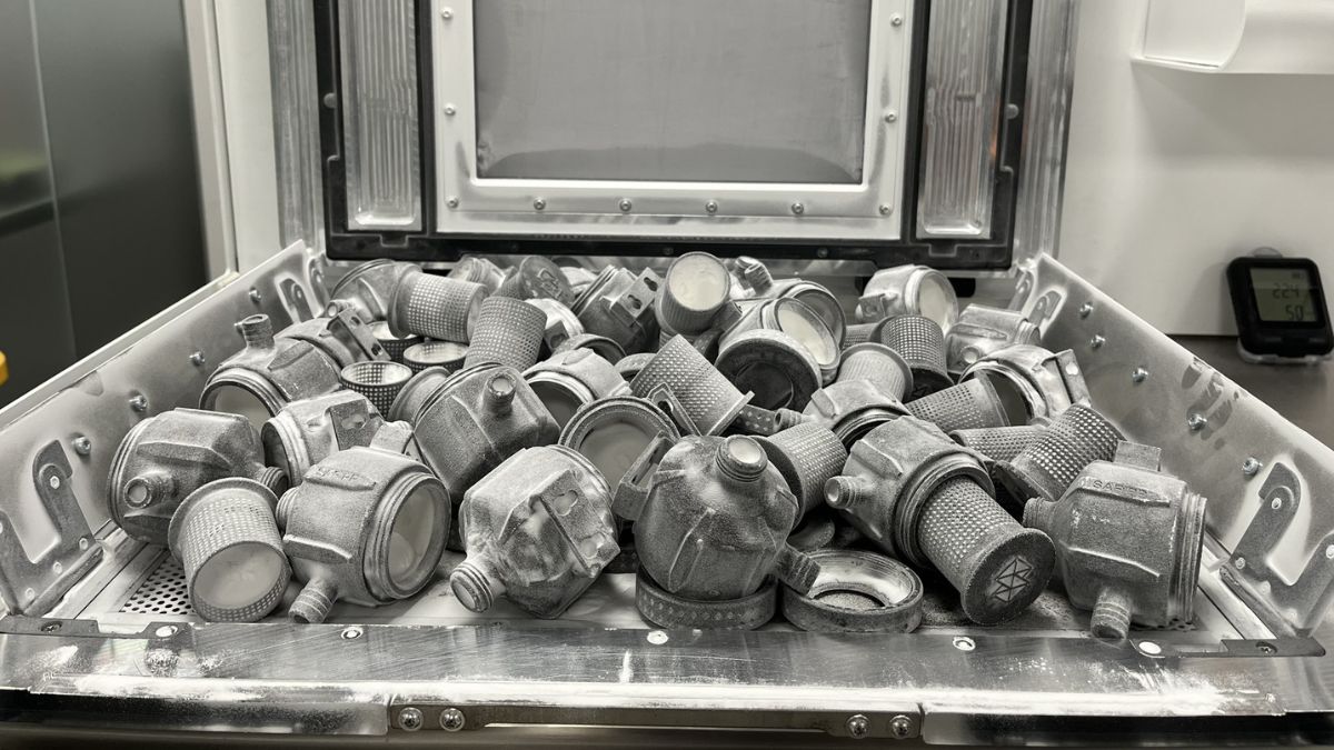 Bin of gray nylon connector housings fresh from a Stratasys H350 SAF print job