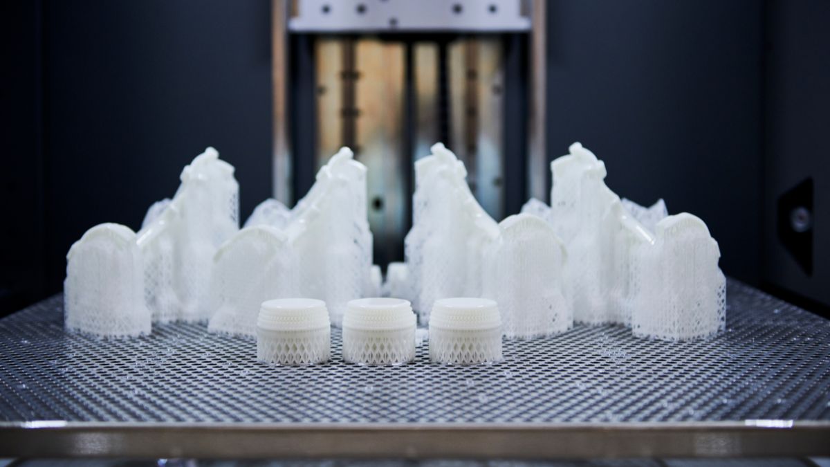 White prototype parts arranged on the build platform inside a Stratasys Neo printer.