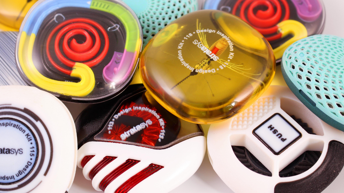 Close-up of colorful 3D-printed PolyJet material samples with varied textures, covers, and labeled design features.