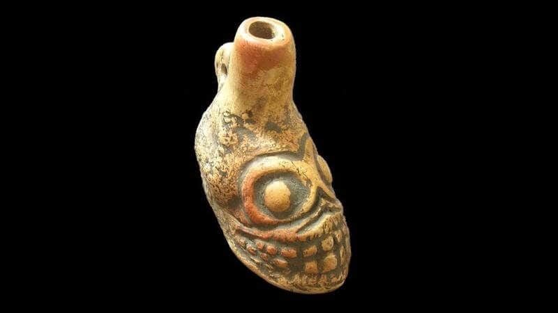 An authentic pre-Columbian Aztec death whistle carved from clay into a skull shape, shown for comparison with the 3D printed SOLIDWORKS replica.