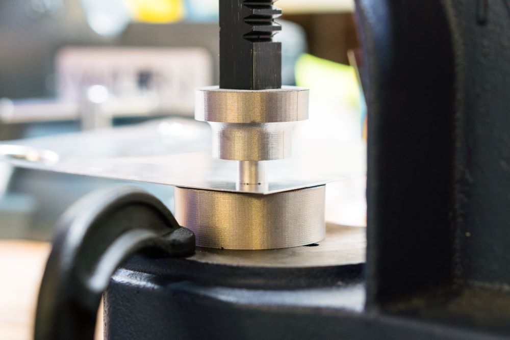 Markforged 3D-printed metal part undergoing strength testing with a compression tool.