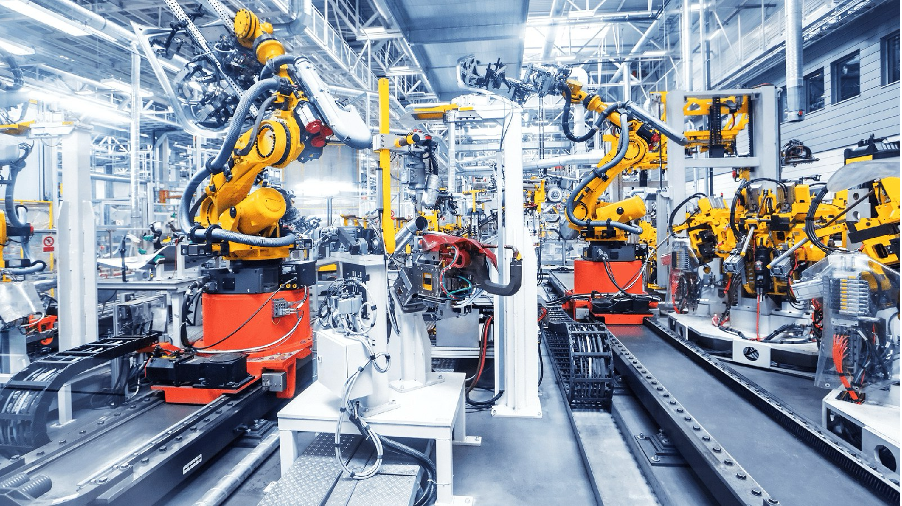 Rows of robotic arms and conveyors in an automated assembly line viewed down the length of the cell