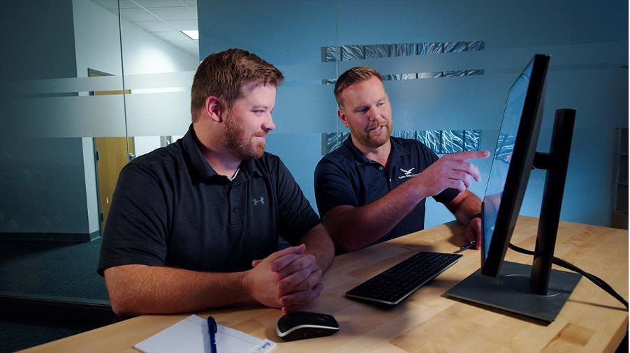 Two Hawk Ridge Systems engineers discussing findings at a monitor, one pointing at the screen