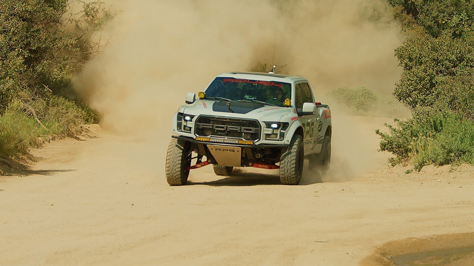 Lifted off-road pickup truck kicking up a cloud of dust on a desert trail