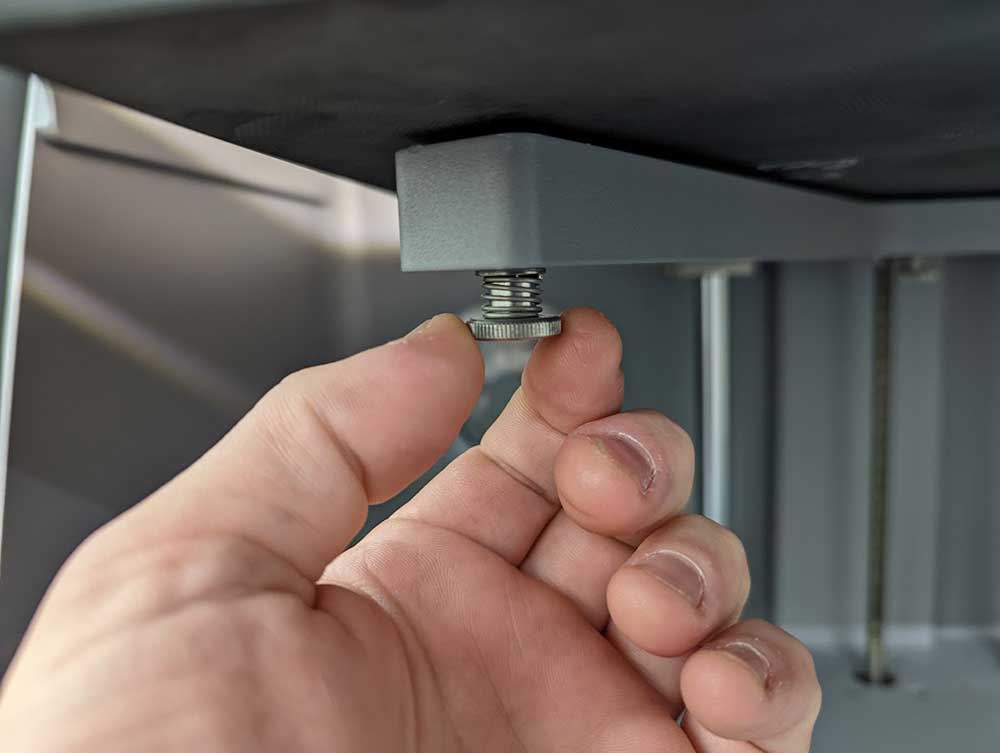 Adjusting screws on Markforged desktop 3D printer for bed leveling