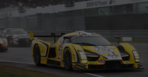 Yellow number 702 GT race car on a wet track riding on Forgeline forged wheels.