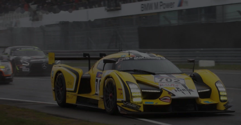 Yellow number 702 GT race car on a wet track riding on Forgeline forged wheels.