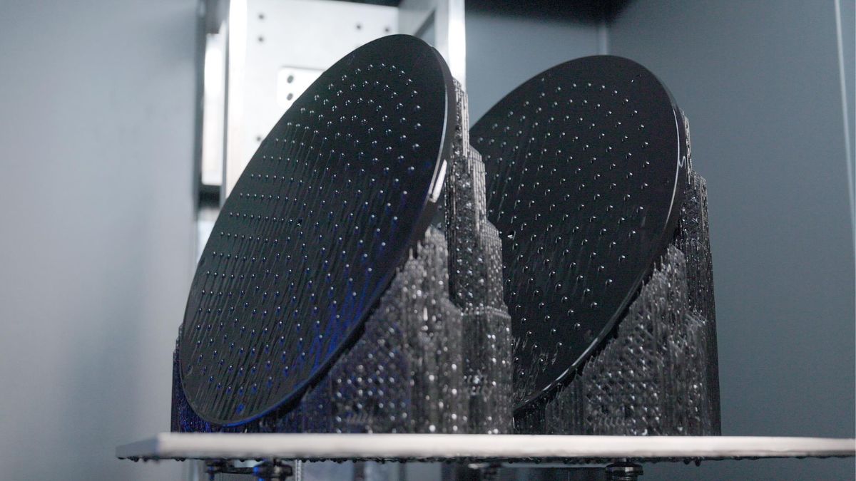 Two circular black parts printing on support structures inside a Stratasys Neo printer.