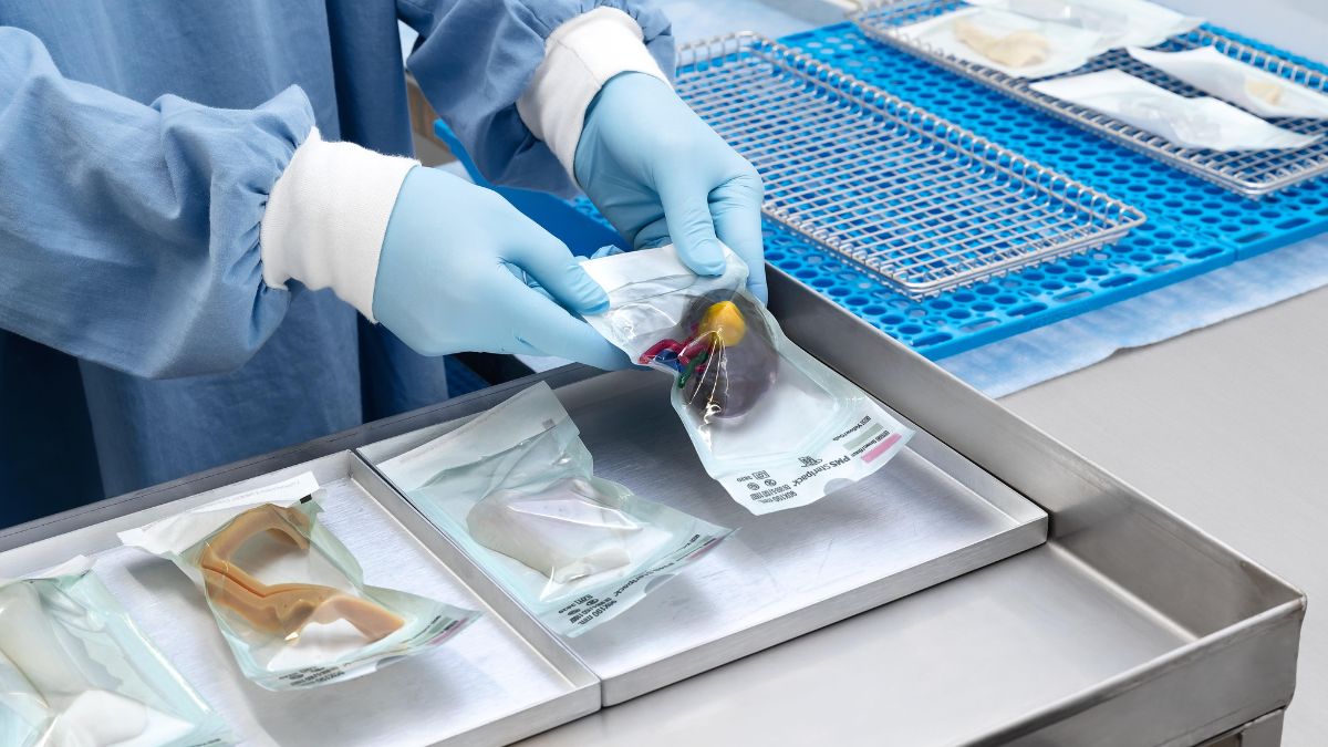 Gloved hands placing a sealed 3D-printed medical model onto a sterilization tray.