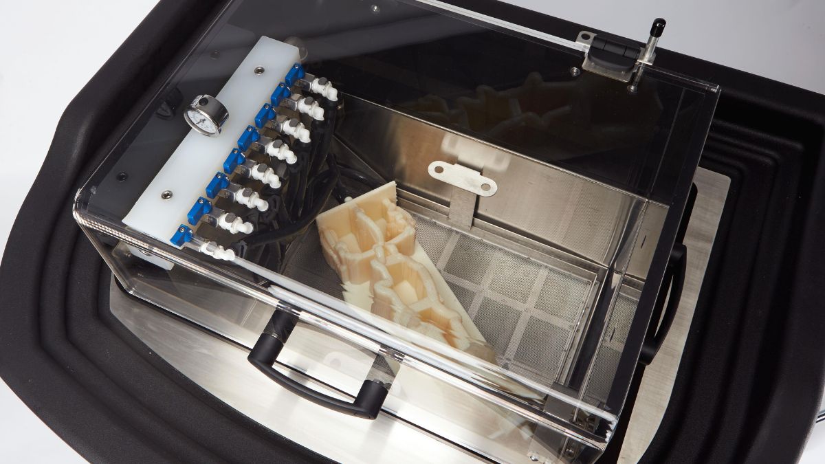 Washing station with printed anatomical model inside a clear enclosed chamber.