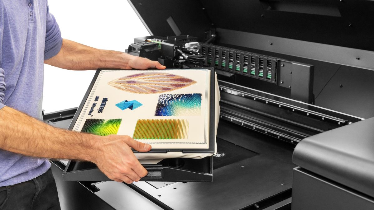 Person removing a 3D printed fabric sample from the print bed of a Stratasys J850 TechStyle 3D printer.