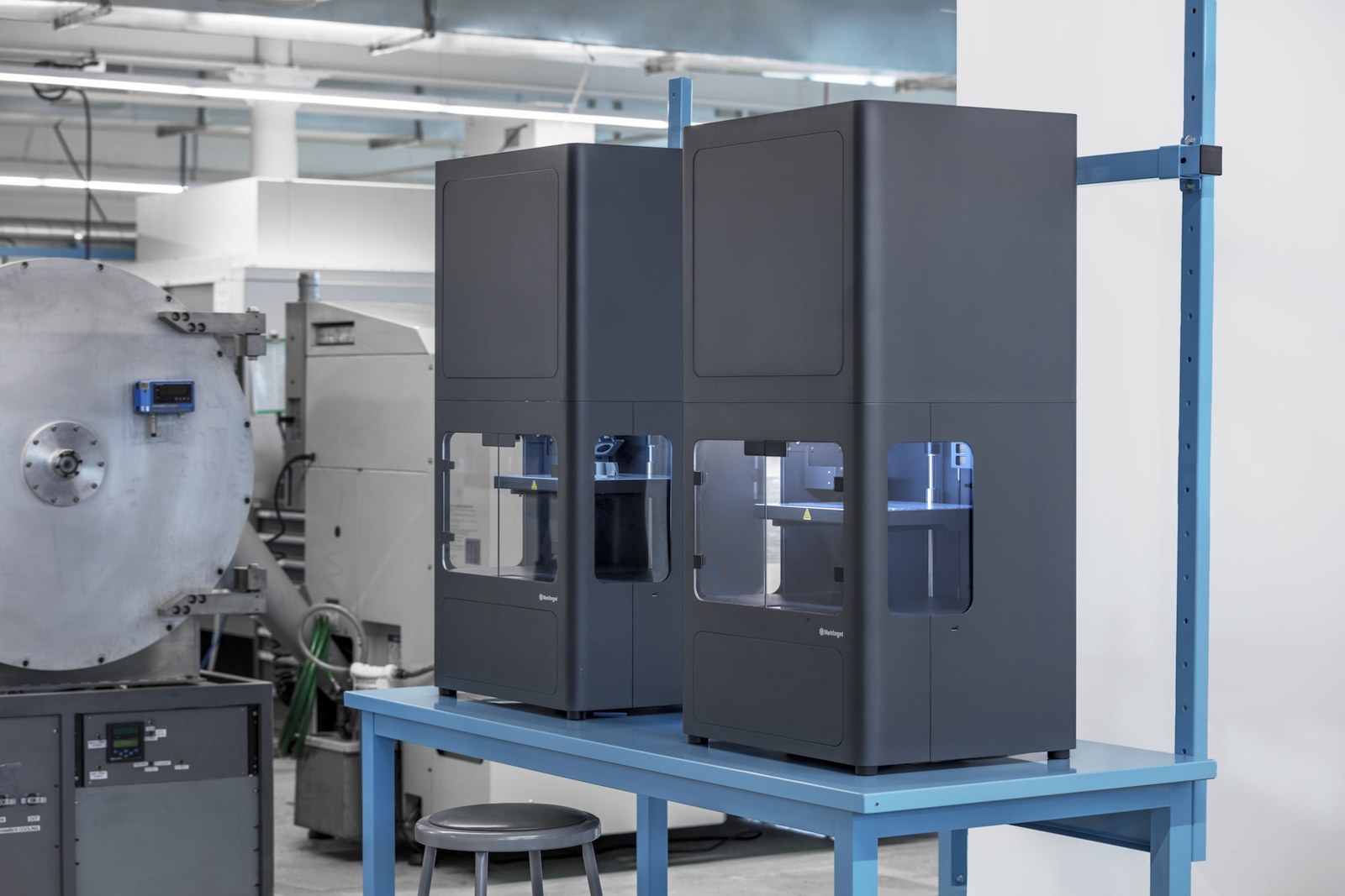 Two Markforged Metal X metal 3D printers on a workbench in a machine shop