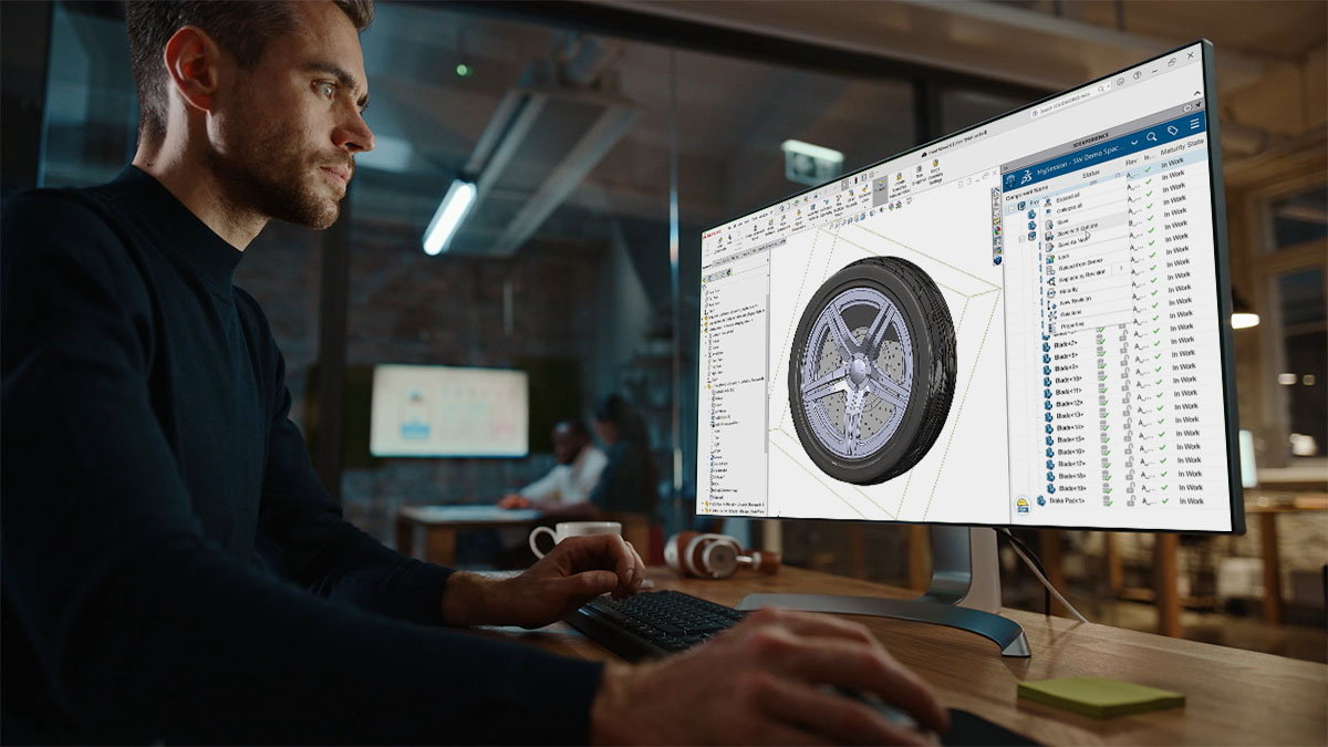 Engineer analyzing a 3D CAD model of a car wheel on a computer monitor in an office setting
