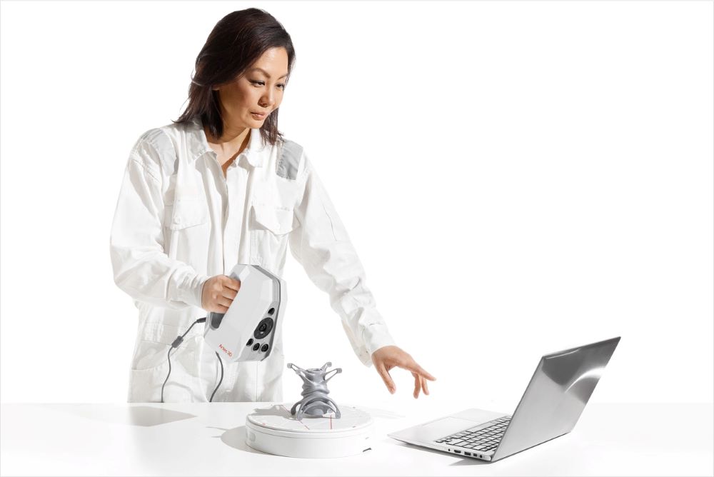 A woman using the Artec Spider II to scan a complex object on a turntable 